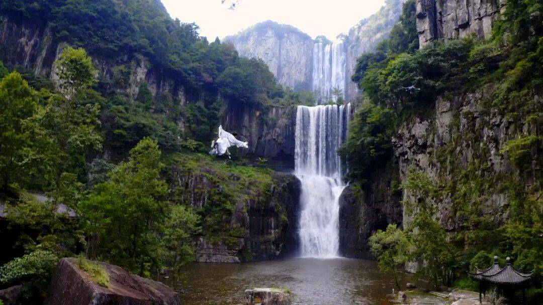 女生瀑布前拍视频,空中突然飘来一排人
